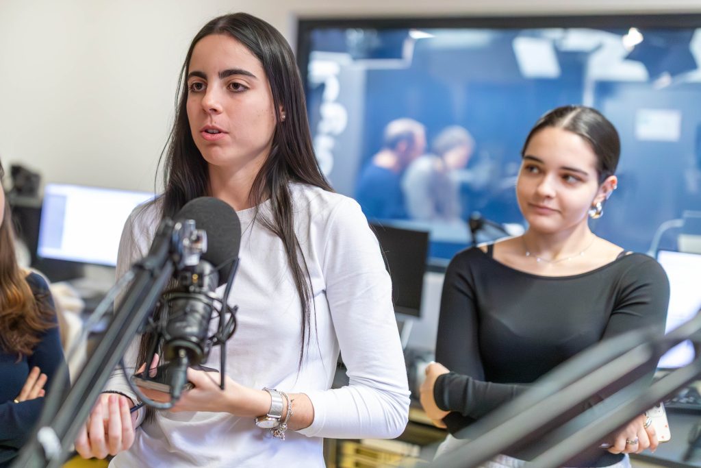 Gruppe von jungen Frauen steht in einem Raum mit gelbem Boden vor einem Fenster