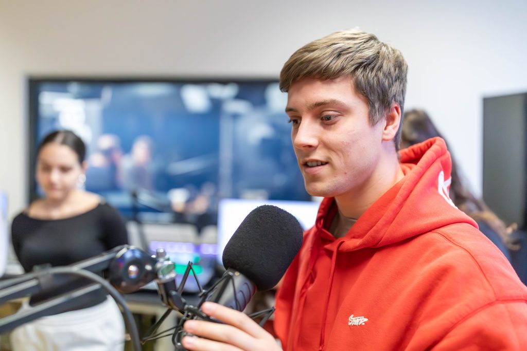 Gruppe von jungen Menschen steht in einem Raum mit gelbem Boden vor einem Fenster