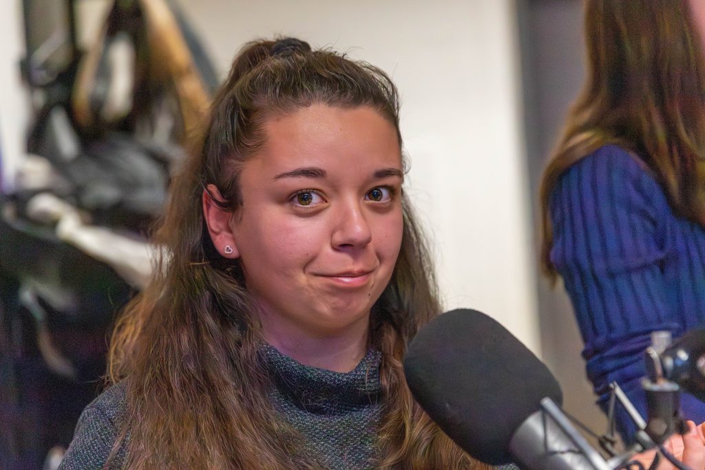 junge Fraue steht in einem Raum mit gelbem Boden vor einem Fenster