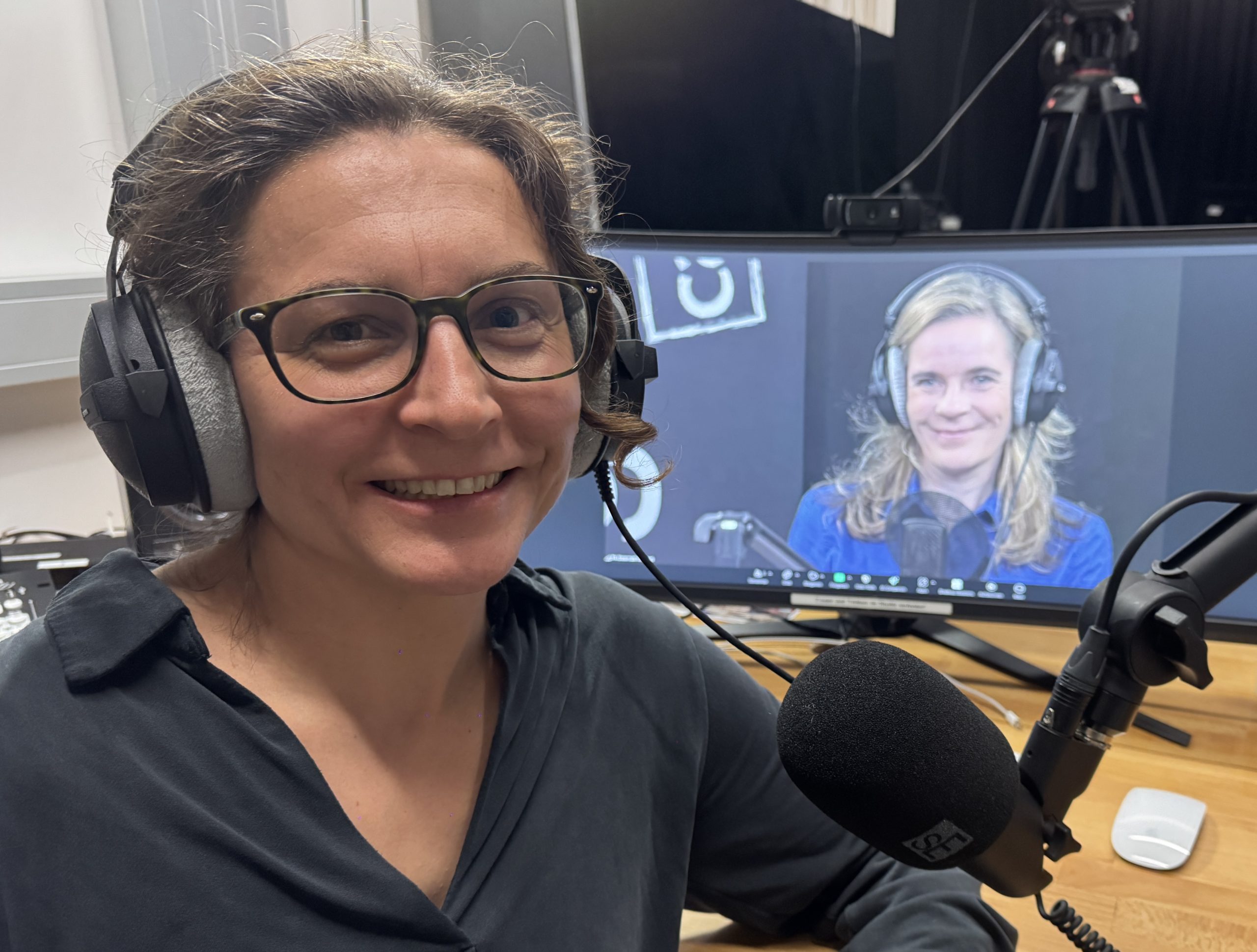 Links im Bild sitzt Prof.in Mag.a Silvia Theiss MSc mit Headset vor einem Mikrofon. Im Hintergrund erscheint auf einem Bildschirm HS-Prof.in Mag.a Dr.in Katharina Heissenberger-Lehofer, ebenfalls mit Headset und Mikrofon.
