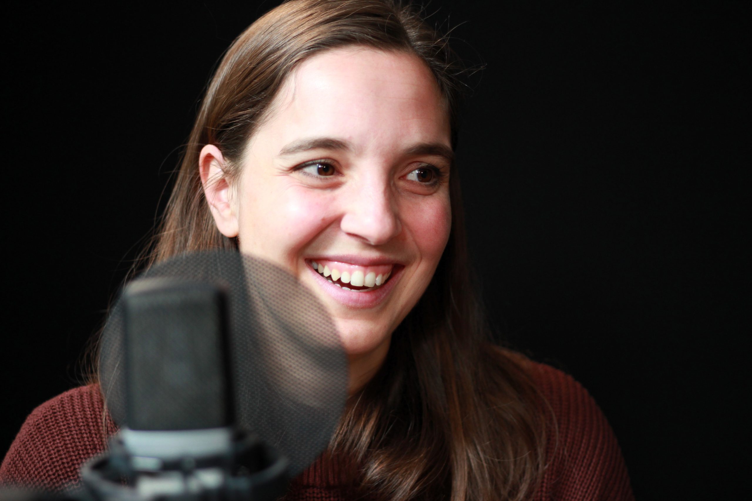 Marie Knabl vor schwarzem Hintergrund mit Mikrofon im Vordergrund.